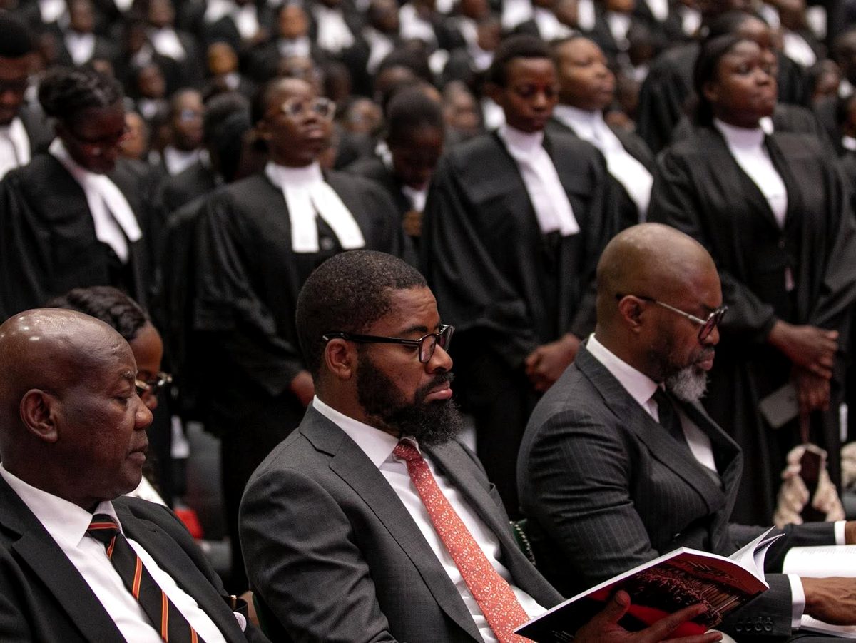Deji Adeyanju seated among guests at a call to bar ceremony, with new wigs standing behind