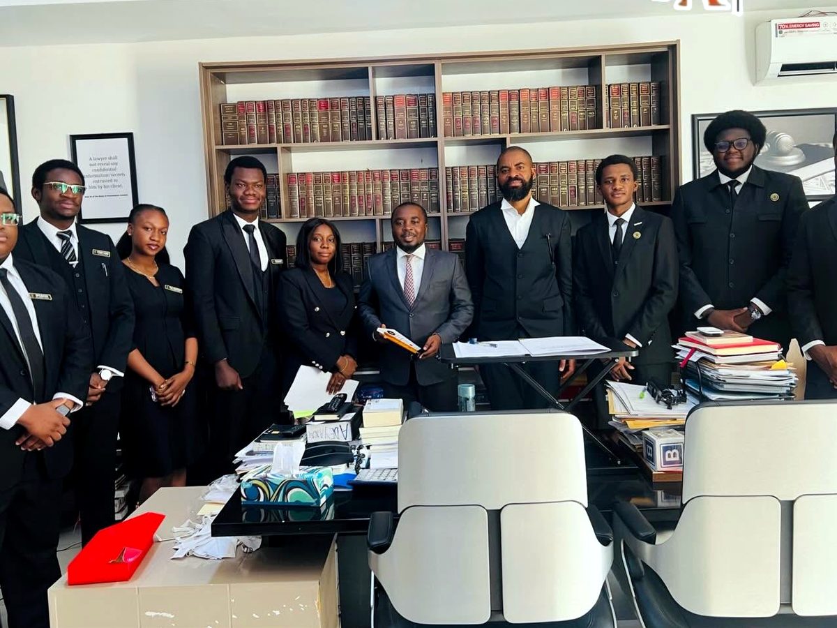 Students and colleagues gathered around the desk in the chambers of Deji Adeyanju & Partners