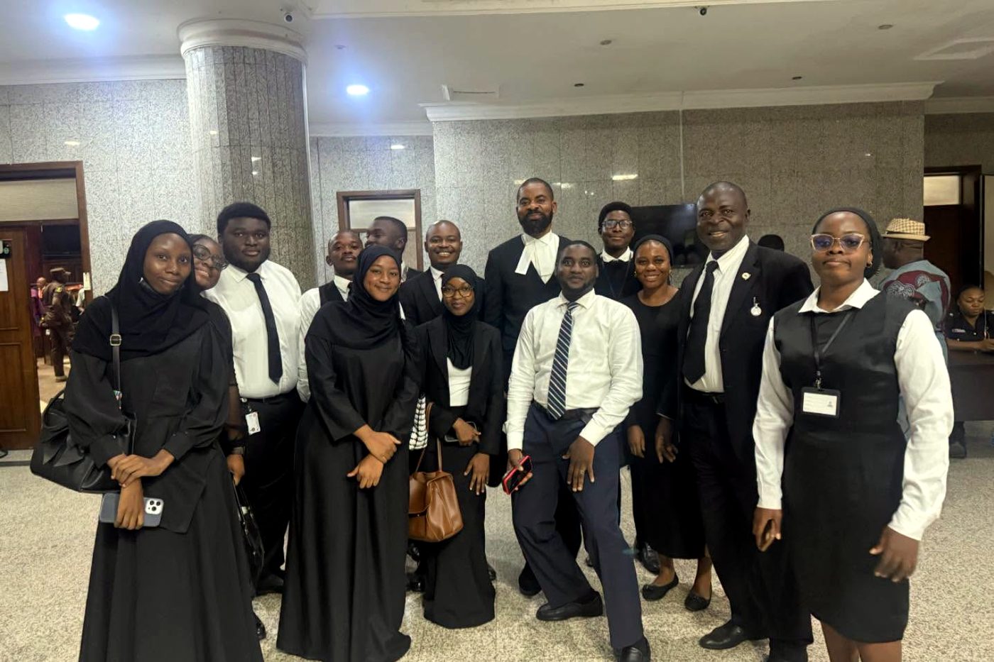 Deji Adeyanju in wig and gown with a group of students at court