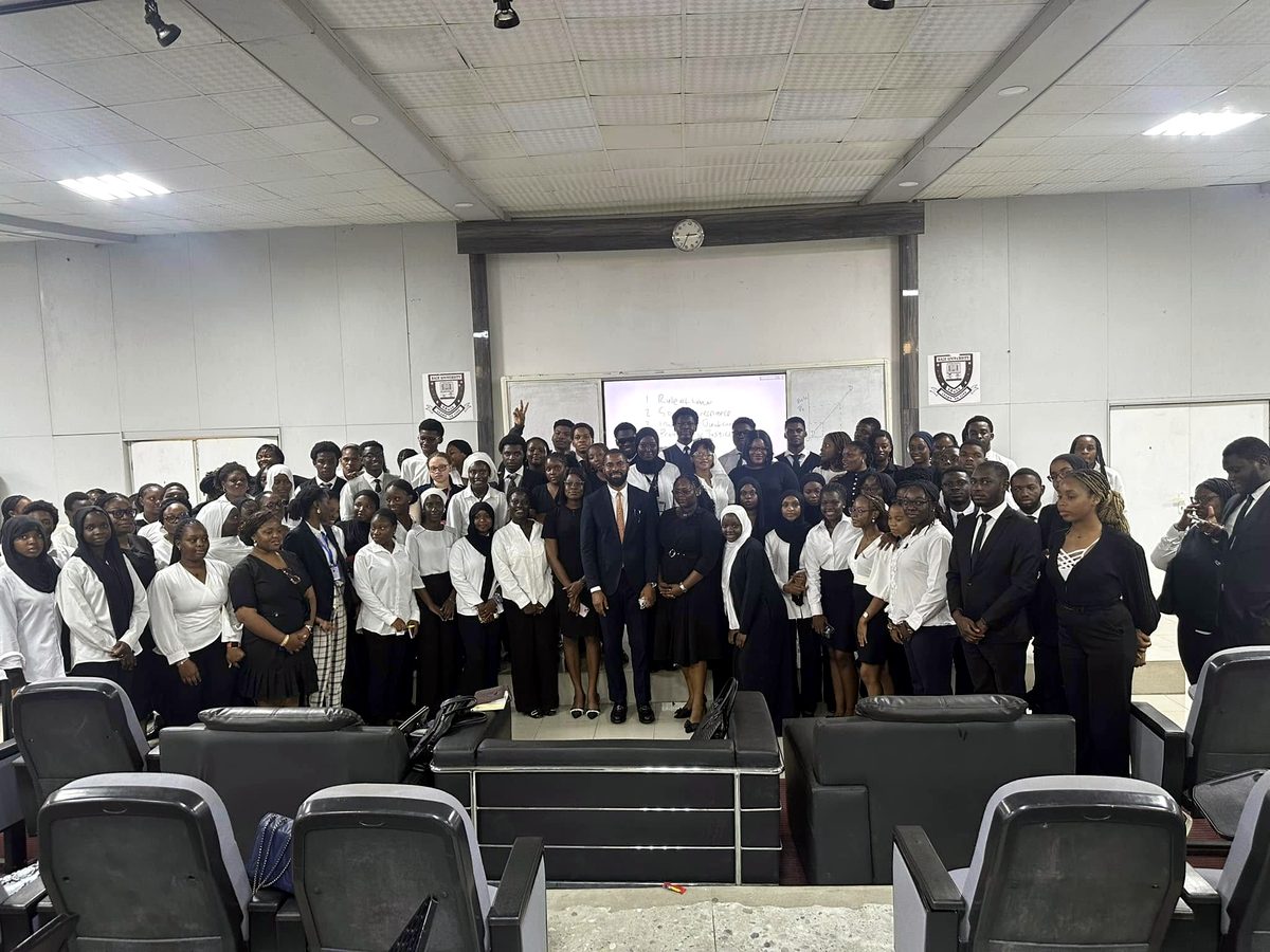 Deji Adeyanju standing with a large group of students in a lecture hall at Baze University